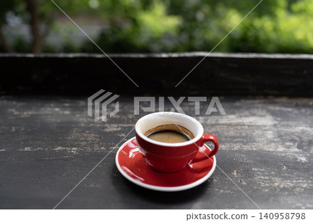Half drink Espresso coffee in a red cup on black grunge wood table Half drink Espresso coffee in a red cup on black grunge wood table 140958798