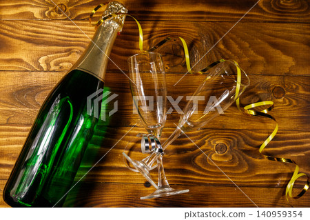 Champagne bottle and two empty champagne glasses on wooden background. Top view Champagne bottle and two empty champagne glasses on wooden background. Top view 140959354