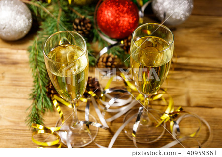 Two glasses of champagne and festive Christmas decorations on wooden table. Christmas and New Year celebration Two glasses of champagne and festive Christmas decorations on wooden table. Christmas and New Year celebration 140959361