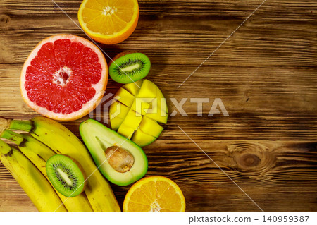 Assortment of tropical fruits on wooden table. Still life with bananas, mango, oranges, avocado, grapefruit and kiwi fruits Assortment of tropical fruits on wooden table. Still life with bananas, mango, oranges, avocado, grapefruit and kiwi fruits 140959387