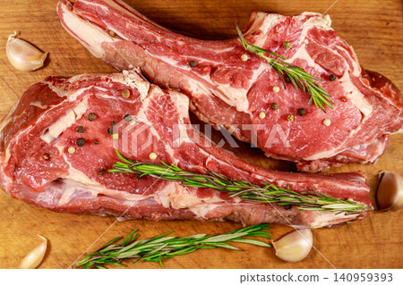 Raw fresh beef rib eye steak on bone with spices, garlic and rosemary on wooden table. Top view Raw fresh beef rib eye steak on bone with spices, garlic and rosemary on wooden table. Top view 140959393