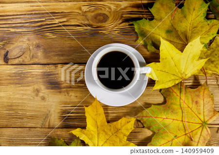 Cup of coffee and autumn maple leaves on wooden table. Top view. Autumn concept Cup of coffee and autumn maple leaves on wooden table. Top view. Autumn concept 140959409