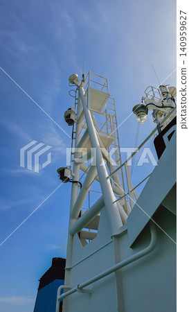 Vertical low angle shot of a white metal industrial ship mast with navigation lights and ladders on a commercial vessel superstructure under a clear blue sky Vertical low angle shot of a white metal industrial ship mast with navigation lights and ladders on a commercial vessel superstructure under a clear blue sky 140959627