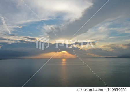 The dramatic light of the setting sun shining across storm clouds and calm seas over the South China Sea The dramatic light of the setting sun shining across storm clouds and calm seas over the South China Sea 140959631