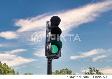Green traffic light shining against a blue sky with clouds Green traffic light shining against a blue sky with clouds 140959719