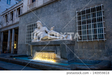 Turin, piedmont, italy. November 20, 2024. Reclining sculpture of po river god fountain illuminated at dusk in piazza cln, historic center of turin, italy Turin, piedmont, italy. November 20, 2024. Reclining sculpture of po river god fountain illuminated at dusk in piazza cln, historic center of turin, italy 140959818