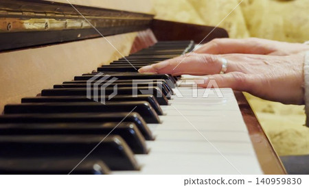 Adult female hands playing a gentle piece of classical music on a brown piano. The scene captures the movement, rhythm and elegance of performance, highlighting beauty of live instrumental play Adult female hands playing a gentle piece of classical music on a brown piano. The scene captures the movement, rhythm and elegance of performance, highlighting beauty of live instrumental play 140959830