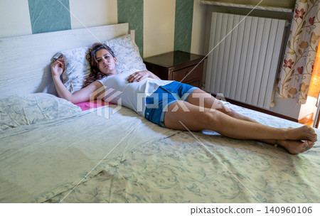 Young woman lying on a bed in a bedroom, thinking and experiencing feelings of sadness, loneliness, and depression, reflecting on personal mental health and emotional well being Young woman lying on a bed in a bedroom, thinking and experiencing feelings of sadness, loneliness, and depression, reflecting on personal mental health and emotional well being 140960106