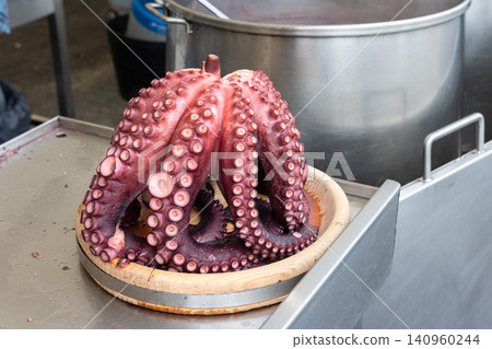 Cooked octopus resting on a wooden plank at a traditional Galician food stall Cooked octopus resting on a wooden plank at a traditional Galician food stall 140960244