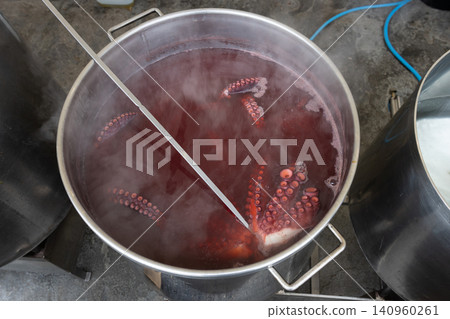 high angle view of boiling octopus in a large stainless steel pot with steam 140960261