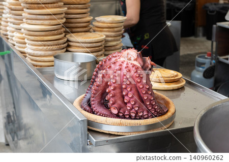 close up of cooked octopus and traditional galician wooden plates at a food stall counter close up of cooked octopus and traditional galician wooden plates at a food stall counter 140960262