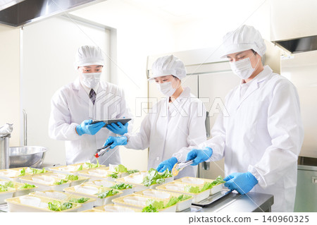 食品廠員工在進行擺盤作業的同時,也檢查工作流程。 食品廠員工在進行擺盤作業的同時,也檢查工作流程。 140960325