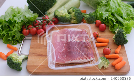 Taking thin jamon slices from package beside farm vegetables on rustic kitchen board Taking thin jamon slices from package beside farm vegetables on rustic kitchen board 140960586