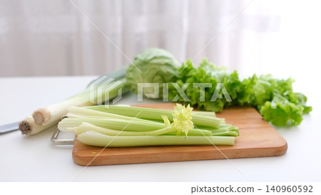 fresh celery stalks on wooden board with cabbage greens and leek in kitchen fresh celery stalks on wooden board with cabbage greens and leek in kitchen 140960592