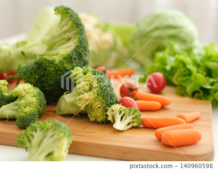 Chopping broccoli pieces and stems with large knife on rustic wooden kitchen board Chopping broccoli pieces and stems with large knife on rustic wooden kitchen board 140960598