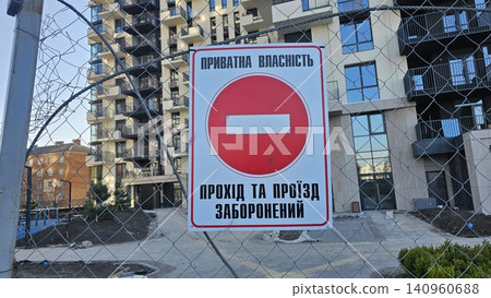 Private property warning sign with no entry traffic symbol on wire fence near modern residential construction site and newly built apartment building Private property warning sign with no entry traffic symbol on wire fence near modern residential construction site and newly built apartment building 140960688