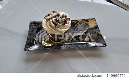 chocolate portioned dessert in a glass cup with a gold spoon on a rectangular plate Sweets on stands. Delicious desserts at the banquet, sponge cakes, shortbread tarts. move camera footage. Close up chocolate portioned dessert in a glass cup with a gold spoon on a rectangular plate Sweets on stands. Delicious desserts at the banquet, sponge cakes, shortbread tarts. move camera footage. Close up 140960751