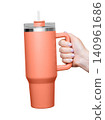 Female Hand Holding 40 oz orange tumbler. Tumbler With Handle, Travel Mug Straw Covers Cup with Lid 140961686