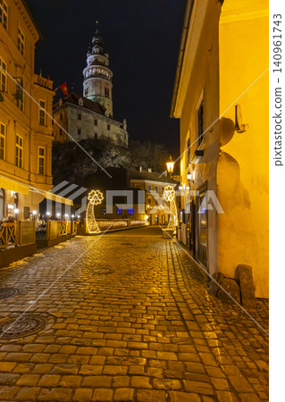 Cesky Krumlov castle tower illuminating historic street at night 140961743