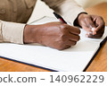 Closeup of a hand holding a pen with a notebook. 140962229