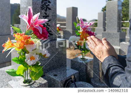 An image of a woman praying at a grave during the Obon festival. An image of a woman praying at a grave during the Obon festival. 140962318
