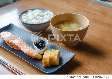 日式早餐包括烤鮭魚、蛋捲、白飯和味噌湯(一份湯,三份小菜)。 日式早餐包括烤鮭魚、蛋捲、白飯和味噌湯(一份湯,三份小菜)。 140962377