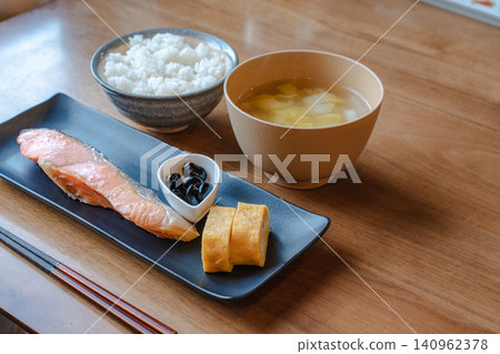 木桌上擺放著日式早餐:烤鮭魚、蛋捲、米飯和味噌湯。 木桌上擺放著日式早餐:烤鮭魚、蛋捲、米飯和味噌湯。 140962378