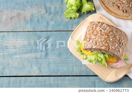 Tasty sandwich with ham on light blue wooden table, flat lay. Space for text Tasty sandwich with ham on light blue wooden table, flat lay. Space for text 140962773