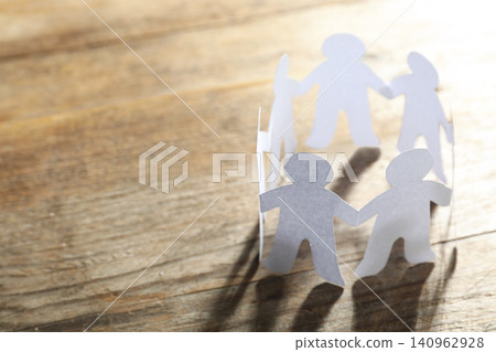 Paper people chain making circle on wooden background, space for text. Unity concept Paper people chain making circle on wooden background, space for text. Unity concept 140962928