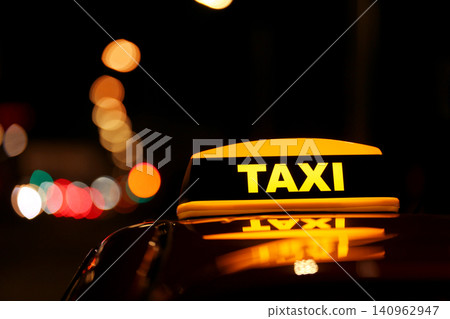 Taxi car with yellow roof sign on city street at night, closeup Taxi car with yellow roof sign on city street at night, closeup 140962947