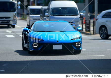 Image of a blue Italian sports car driving through a city street. Image of a blue Italian sports car driving through a city street. 140962996
