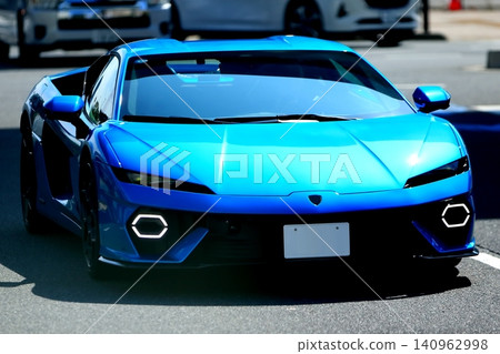 Image of a blue Italian sports car driving through a city street. Image of a blue Italian sports car driving through a city street. 140962998