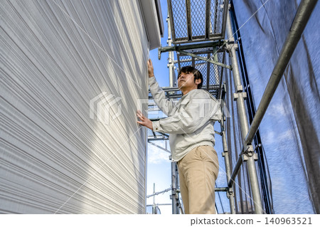 The site supervisor conducts a final check of the new exterior walls and roof renovation. The site supervisor conducts a final check of the new exterior walls and roof renovation. 140963521