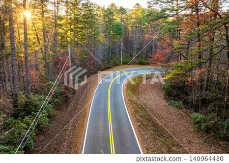 Winding forest road in Tennessee Appalachians during fall. Car traveling through mountain woods under glowing autumn leaves Winding forest road in Tennessee Appalachians during fall. Car traveling through mountain woods under glowing autumn leaves 140964480