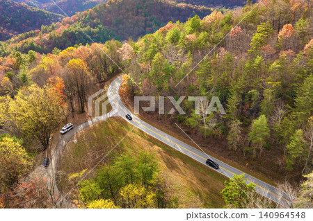 Golden autumn landscape in Appalachian mountains of North Carolina. Forest road winds through hills with vibrant fall foliage Golden autumn landscape in Appalachian mountains of North Carolina. Forest road winds through hills with vibrant fall foliage 140964548