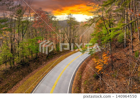 Winding forest road in Tennessee Appalachians during fall. Car traveling through mountain woods under glowing autumn leaves 140964550