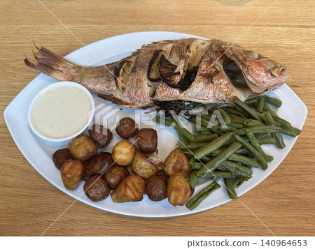A plate of whole roasted sea bream and roasted potatoes served at a Mediterranean restaurant. A plate of whole roasted sea bream and roasted potatoes served at a Mediterranean restaurant. 140964653