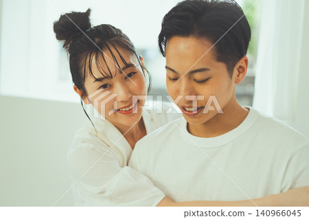A close-up portrait of a couple, with the woman leaning against the man from behind and smiling at the camera. A close-up portrait of a couple, with the woman leaning against the man from behind and smiling at the camera. 140966045
