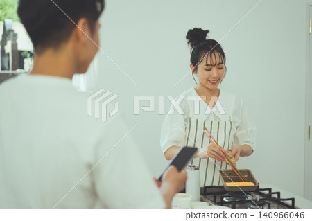 廚房場景,一名女子小心翼翼地捲著蛋捲,一名男子在一旁看著。 廚房場景,一名女子小心翼翼地捲著蛋捲,一名男子在一旁看著。 140966046