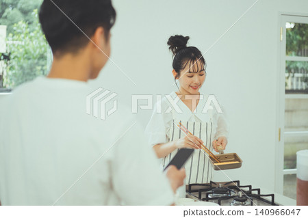 廚房場景,一位女士正在一位男士面前仔細地煎雞蛋。 廚房場景,一位女士正在一位男士面前仔細地煎雞蛋。 140966047