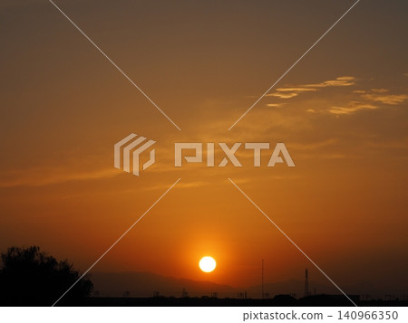 The sun sets in the western sky, which is painted orange. The sun sets in the western sky, which is painted orange. 140966350