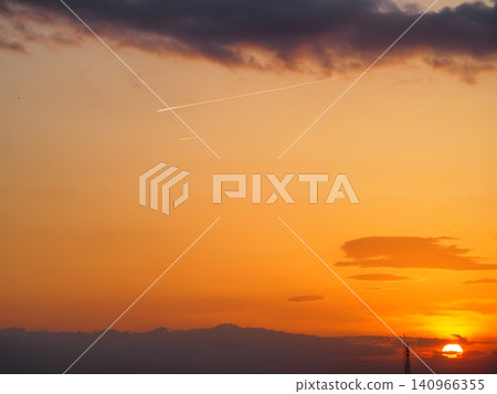 An orange sunset sky with lingering contrails. An orange sunset sky with lingering contrails. 140966355