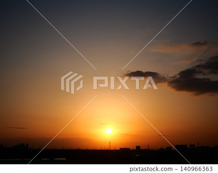 The sun sets in the western sky, which is painted orange. The sun sets in the western sky, which is painted orange. 140966363