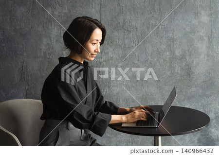 Woman using a laptop at a table Lifestyle image Woman using a laptop at a table Lifestyle image 140966432