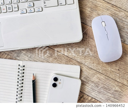 A minimalist workspace with a laptop, smartphone, and wireless mouse. A minimalist workspace with a laptop, smartphone, and wireless mouse. 140966452
