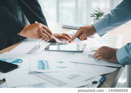 Business professionals analyzing financial charts on smartphone with printed reports, calculator and documents on office desk, showing investment planning and data review. Business professionals analyzing financial charts on smartphone with printed reports, calculator and documents on office desk, showing investment planning and data review. 140966698