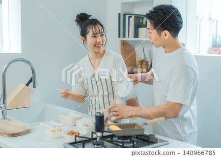 A kitchen scene where a couple is facing each other and chatting with smiles on their faces while preparing lunch. A kitchen scene where a couple is facing each other and chatting with smiles on their faces while preparing lunch. 140966785