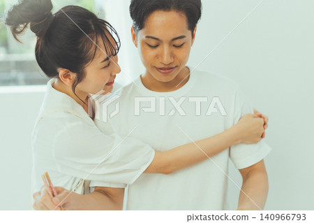 She puts her arms around her boyfriend as he cooks, showing her affection. She puts her arms around her boyfriend as he cooks, showing her affection. 140966793