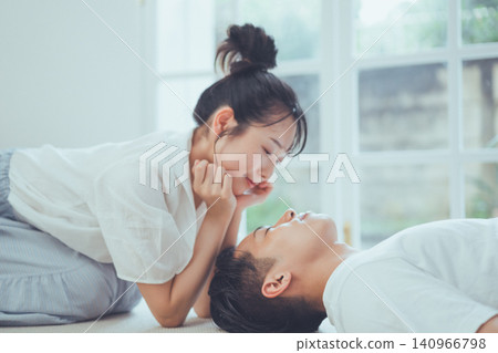 A sweet and romantic moment: a woman smiles as she peers into the face of a man lying down. A sweet and romantic moment: a woman smiles as she peers into the face of a man lying down. 140966798