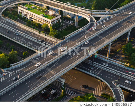 Aerial view captures complex elevated highway structure carrying moving vehicles through a modern urban landscape in China at dusk Aerial view captures complex elevated highway structure carrying moving vehicles through a modern urban landscape in China at dusk 140966857